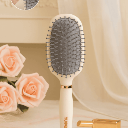 Brosse à cheveux antistatique à coussin d’air couleur beige avec picots souples, posée sur une table avec roses et rouge à lèvres doré